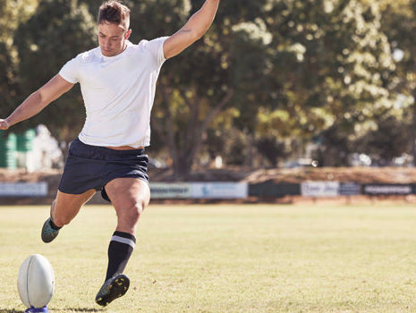 rugby player kicking ball