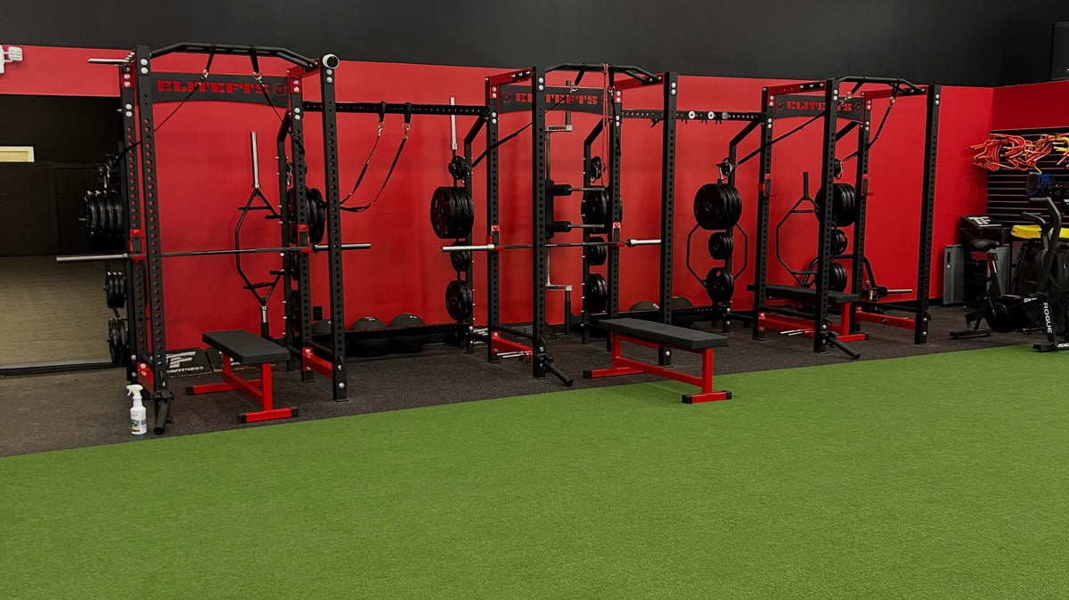 Red and black training racks beside green turf at Athletes By Legacy in Franklin, Tennessee