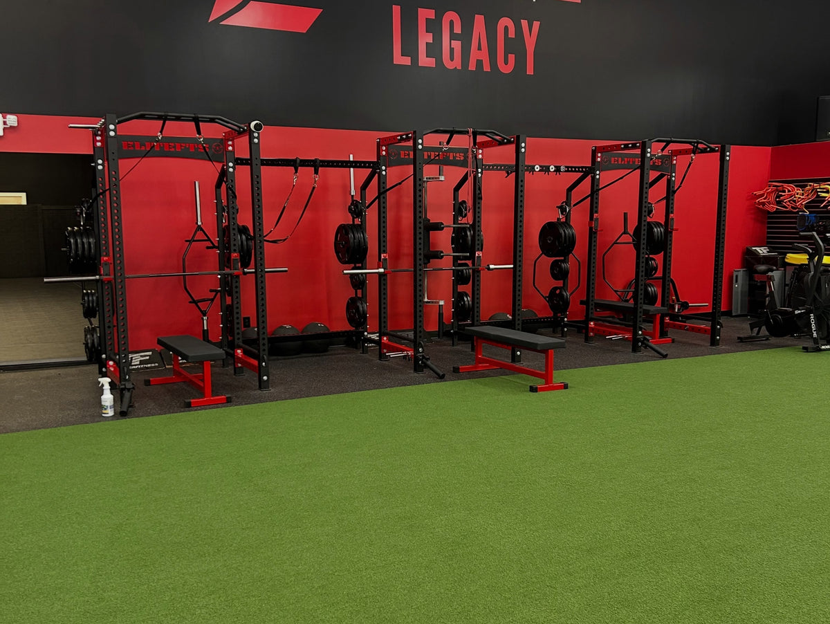 Red and black training racks beside green turf at Athletes By Legacy in Franklin, Tennessee