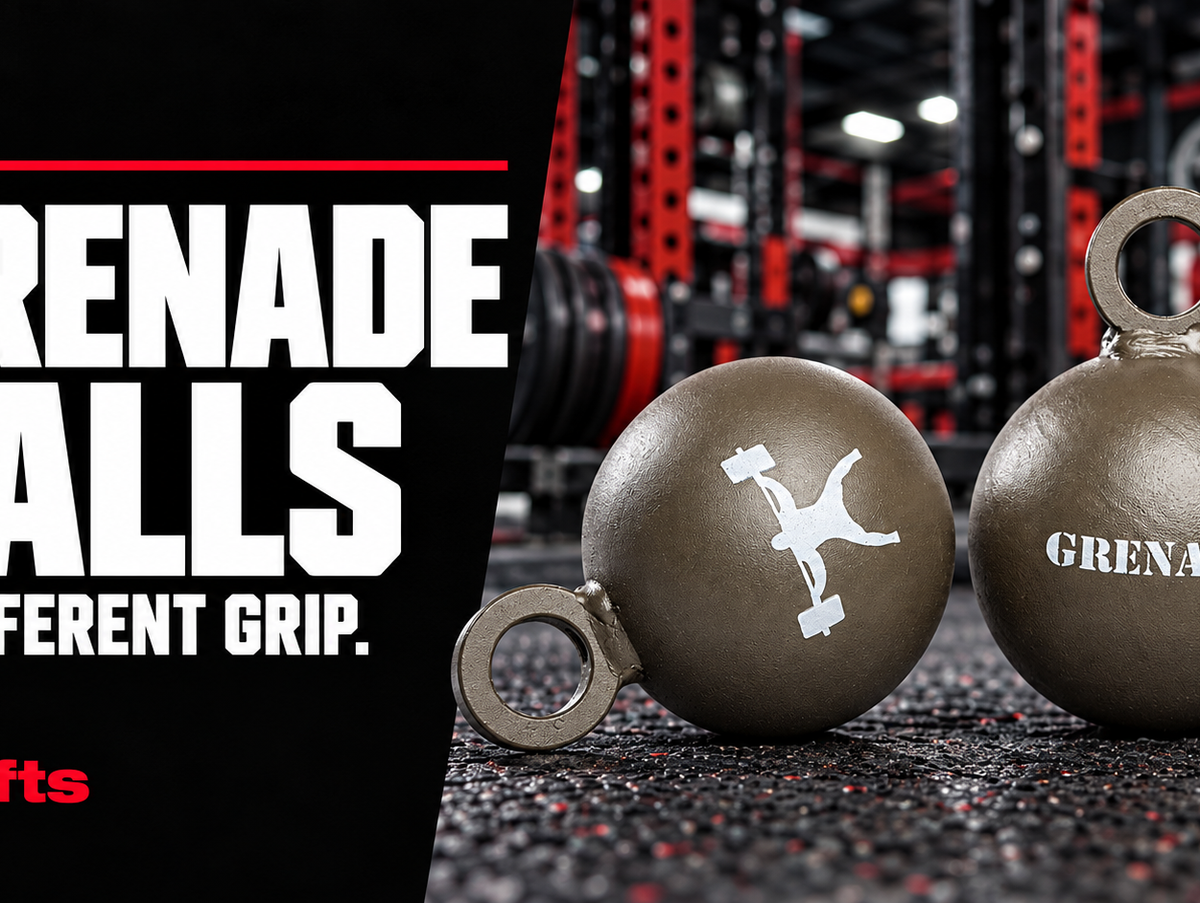 Two olive-drab elitefts Grenade Balls with circular attachment eyes in a red-and-black gym, beside the words Grenade Balls: A Different Grip.