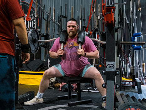 man squatting on box with ssb bar on back