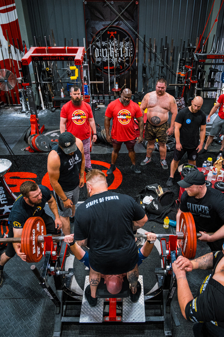 Group of people working out in a gym with weights and exercise equipment.