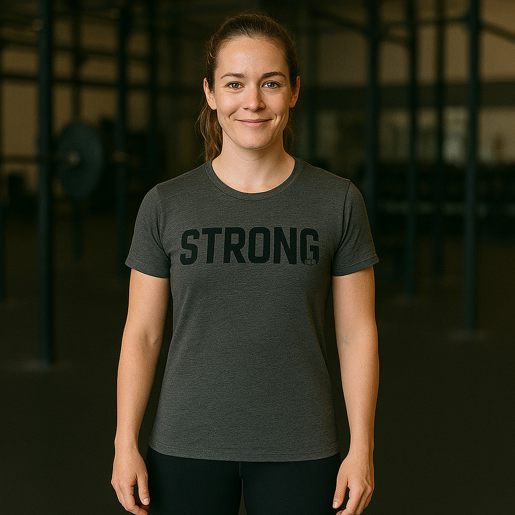Woman wearing a dark gray t-shirt with 'STRONG' printed on it in a gym setting-all-groups