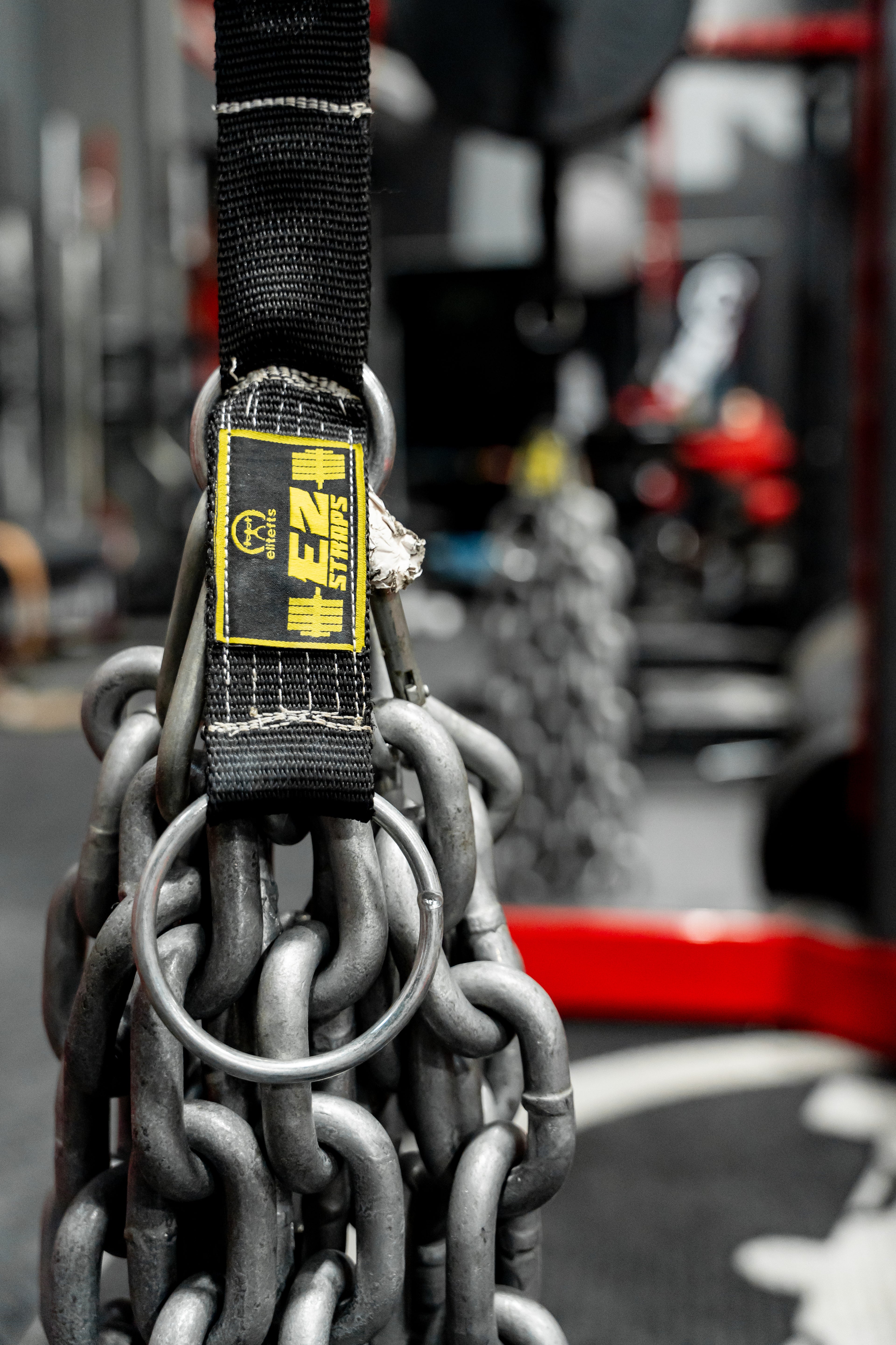 Close-up of a chain with a black strap and yellow label in a blurred indoor setting