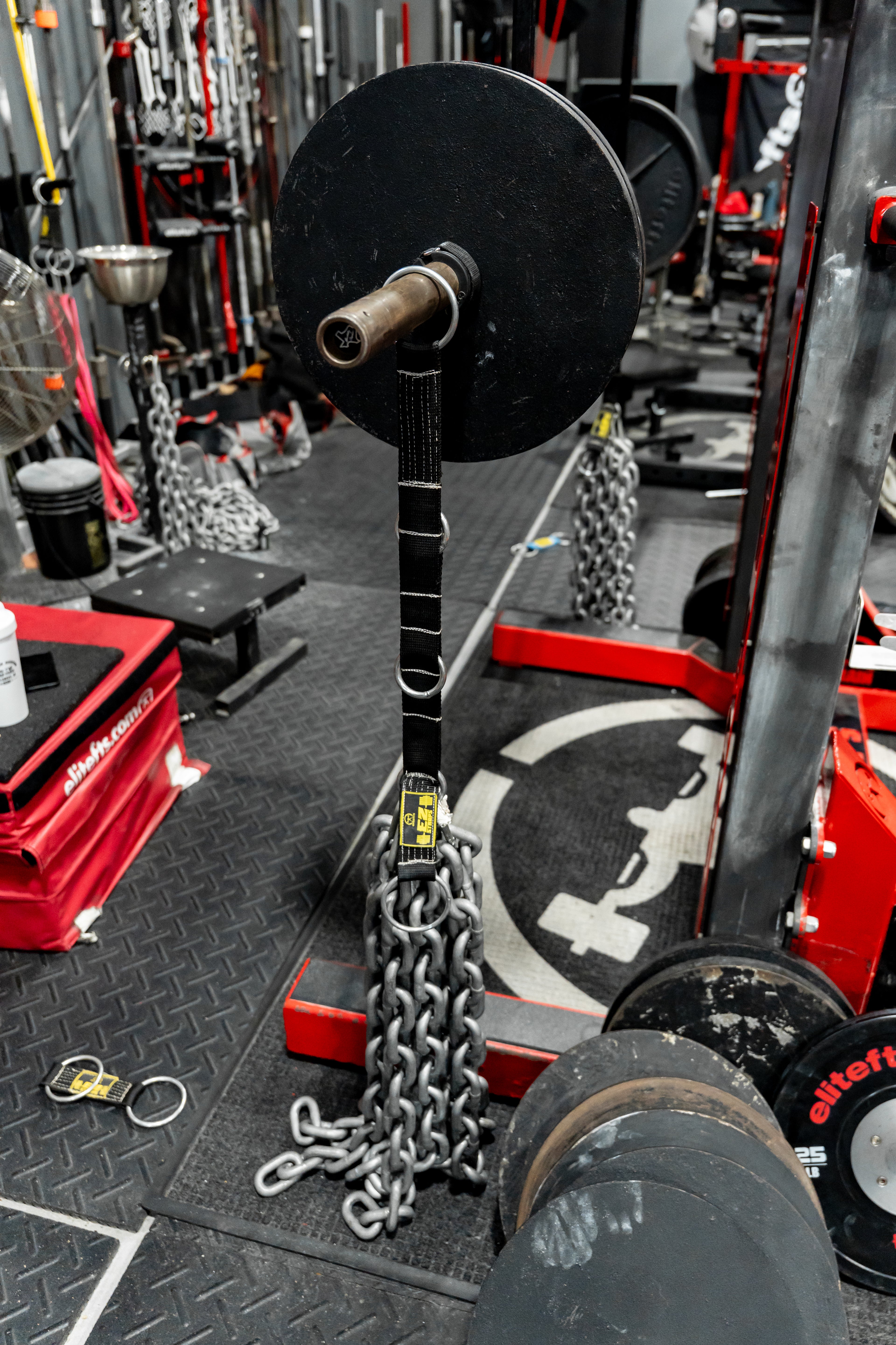 Barbell with weights on a gym floor with various equipment in the background