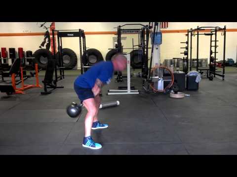 Person lifting a kettlebell in a gym setting