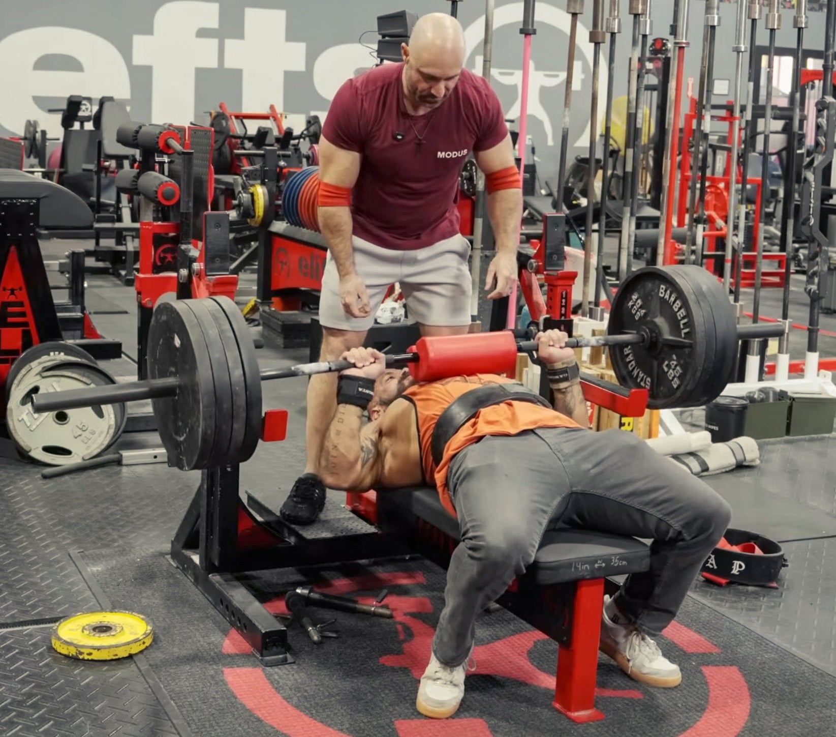 Person bench pressing with a spotter in a gym setting