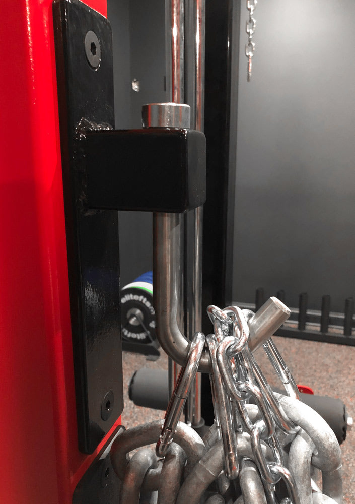 Close-up of a red vehicle with a black metal bracket and chain attached, on a blurred background.