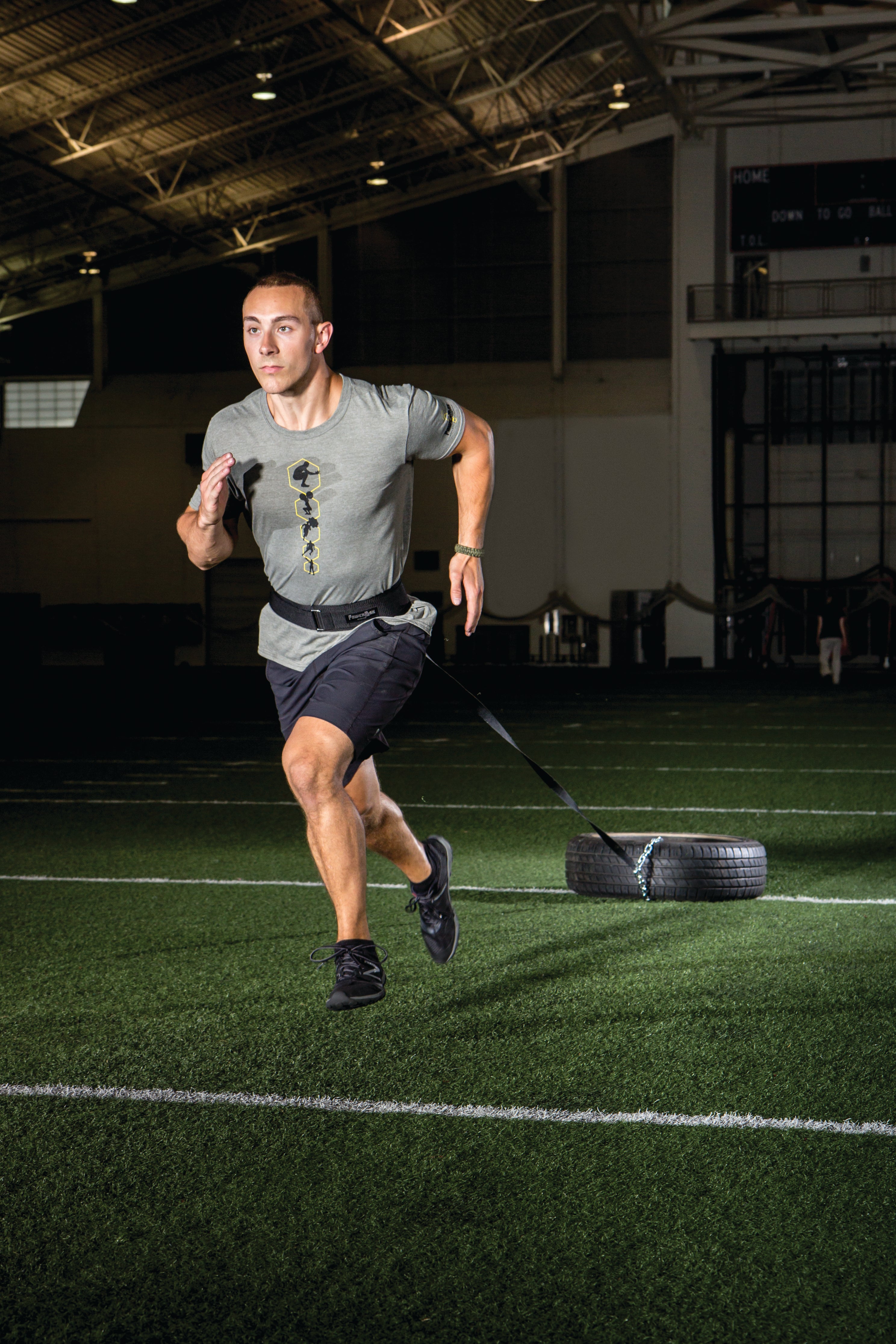 Person running on a sports field with a tire in the background