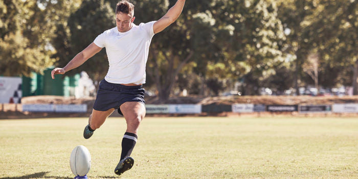 rugby player kicking ball
