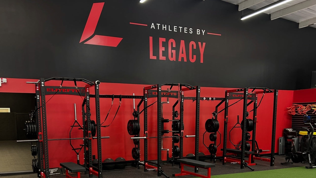 Red and black training racks beside green turf at Athletes By Legacy in Franklin, Tennessee