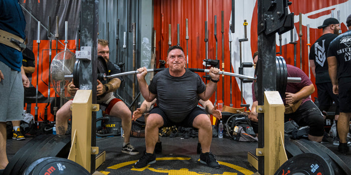 man squatting with cambered bar