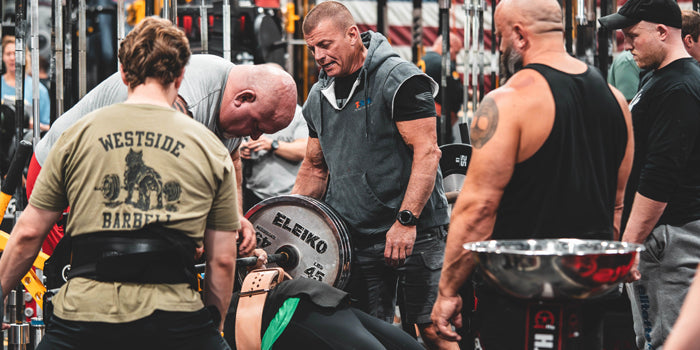 lifters surrounding guy bench pressing