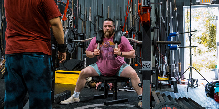 man squatting on box with ssb bar on back