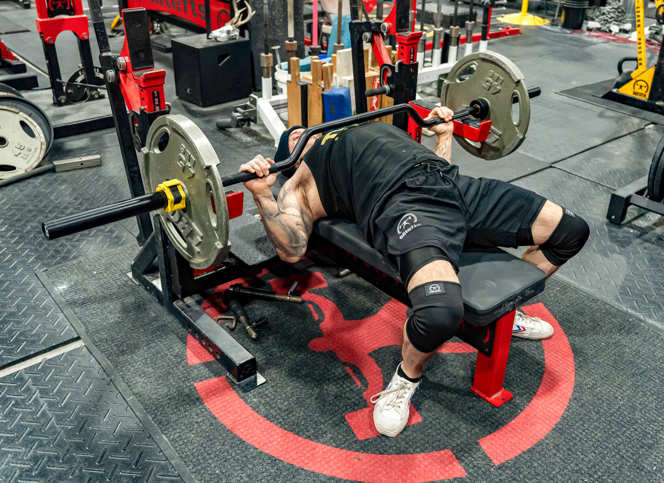 Person performing a bench press with weights in a gym setting