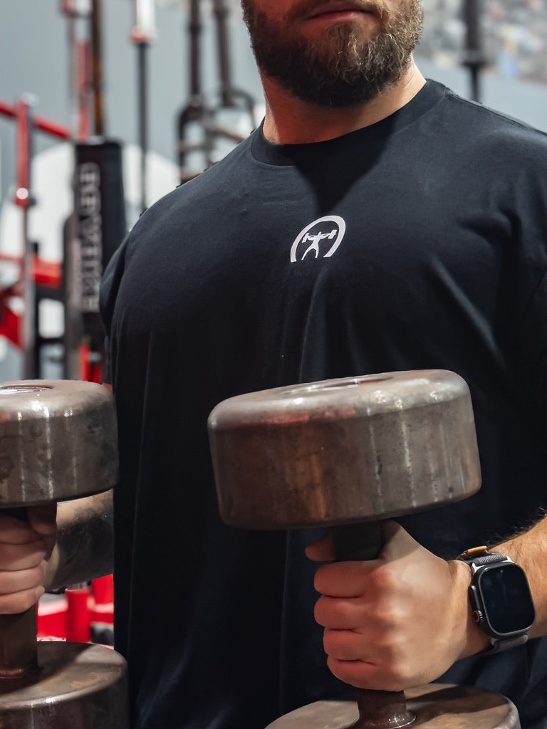 Person holding two dumbbells in a gym setting