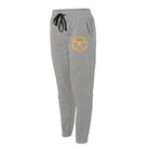 a pair of gray fleece jogger pants with the with a yellow coin decal on the left pant leg