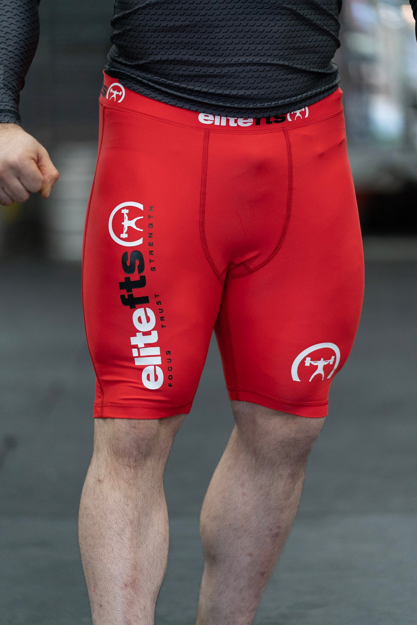 someone wearing a pair of red compression shortswith EliteFTS decals on various parts of the product