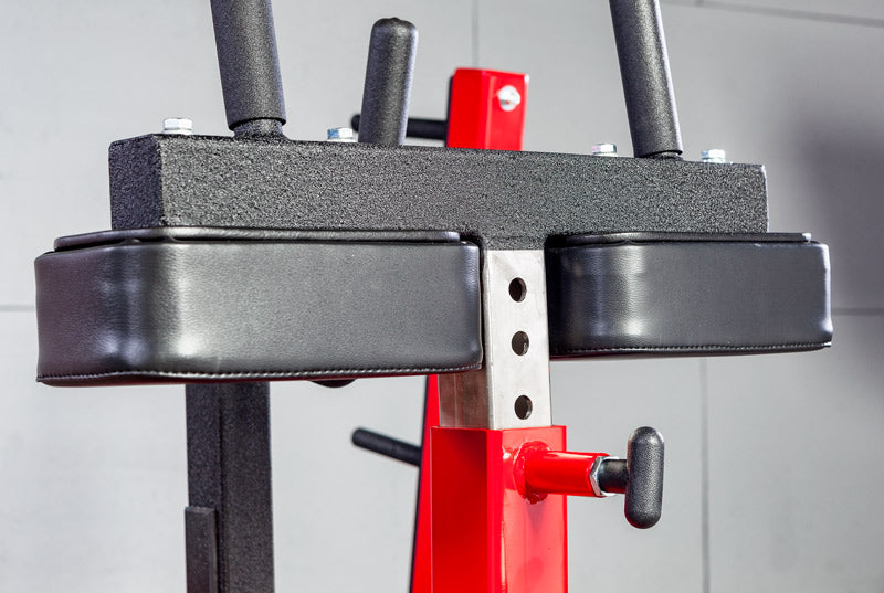 Close-up of a weightlifting barbell with red and black weights on a gray background