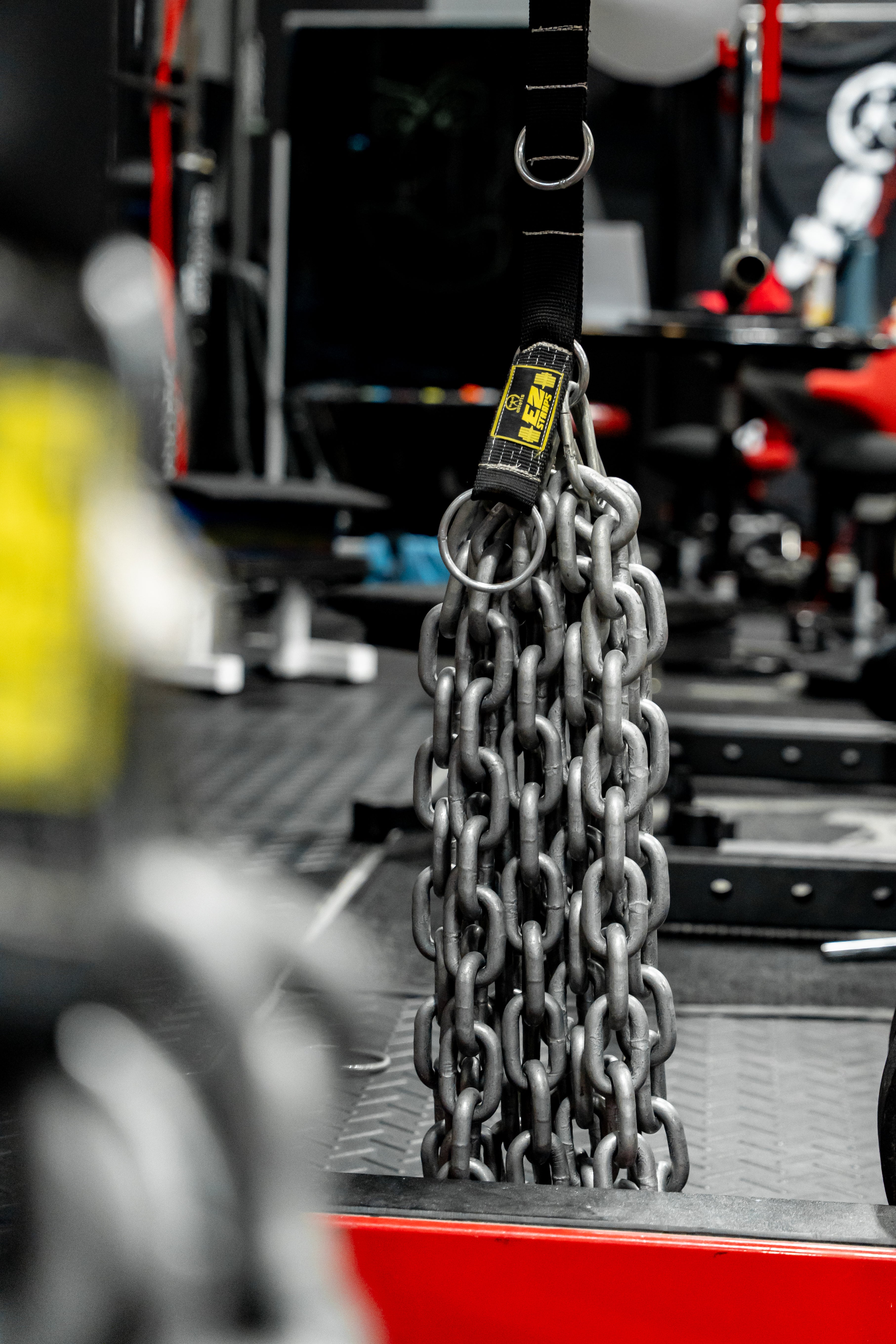 Heavy chain with a yellow tag on a blurred workshop background