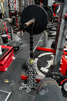 Barbell with weights on a gym floor with various equipment in the background