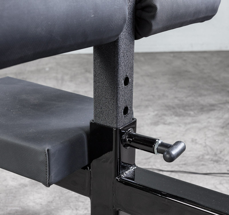 Close-up of a weight bench with padding and adjusting mechanism on a concrete floor.