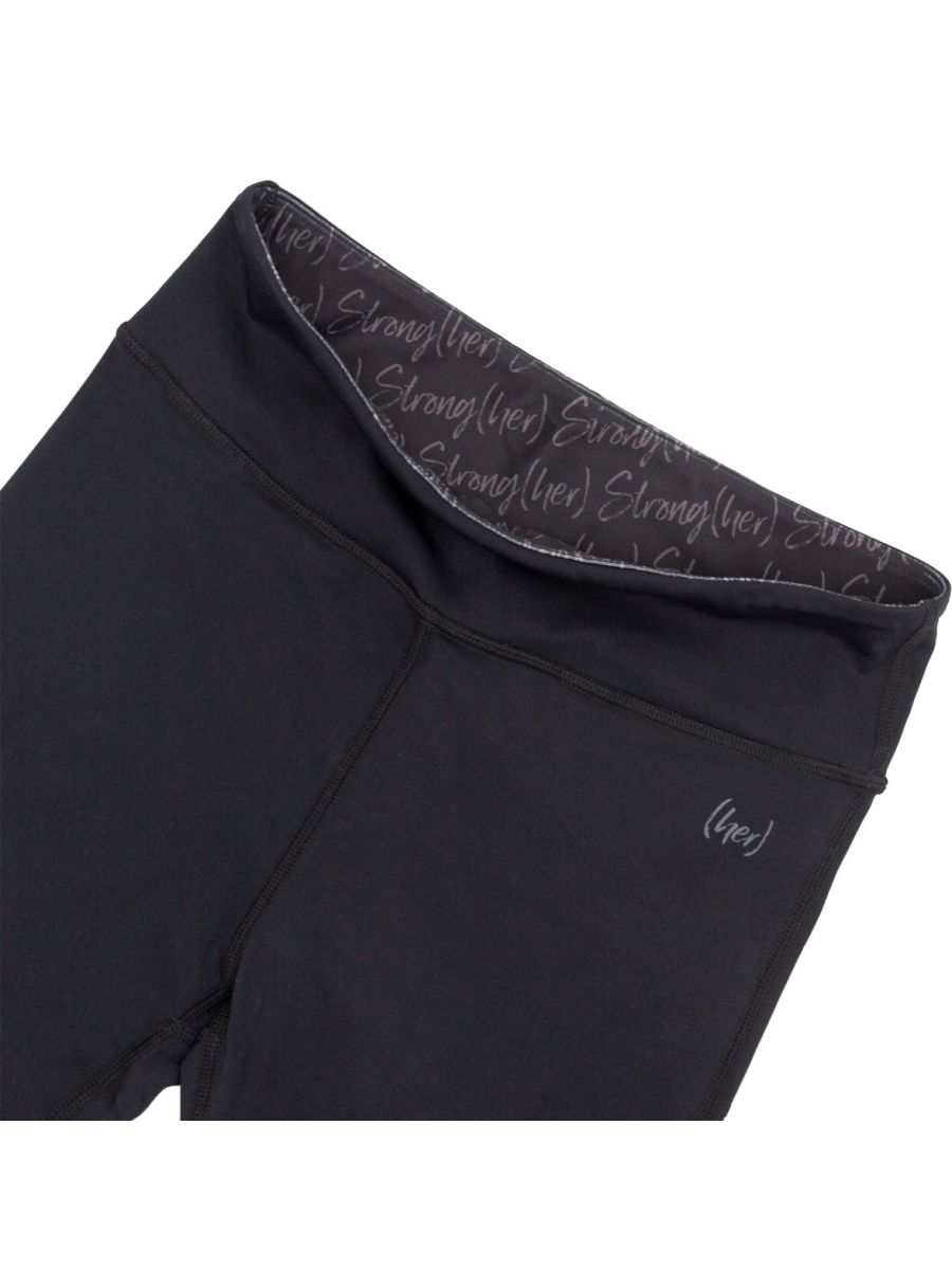 Black leggings with text pattern on waistband against a white background