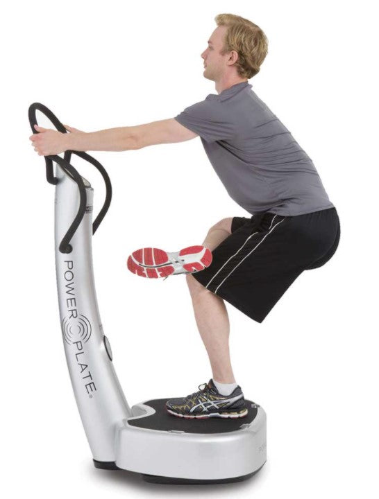 Person using a Power Plate vibration machine on a white background
