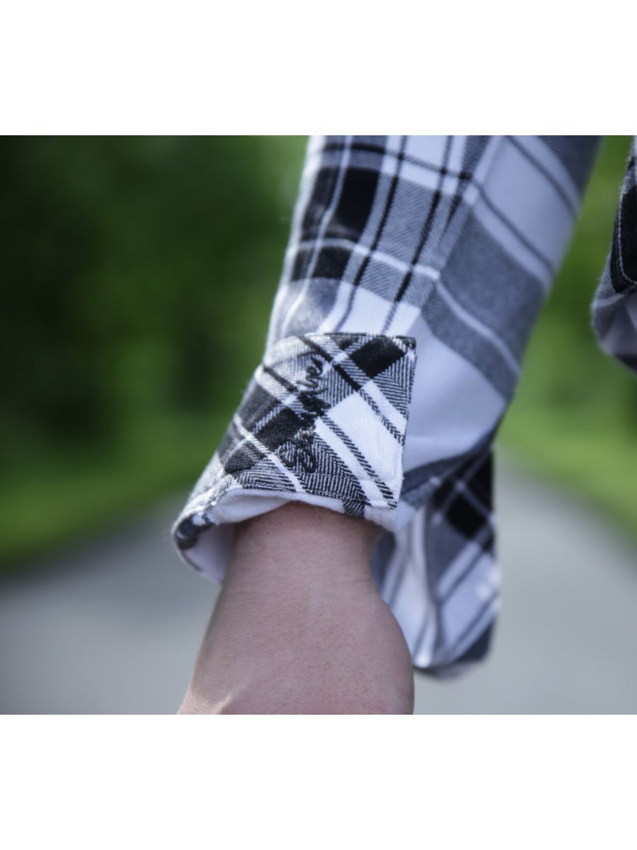 Close-up of a person wearing a plaid shirt with rolled-up sleeves, blurred background