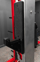 Gym equipment with red and black components on a gray floor.