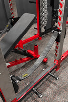 Squat rack with weight plates and bench on a concrete floor