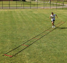 Person running on a grassy field with a long ladder training tool.