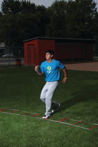 Person running on a grassy field with a building and trees in the background